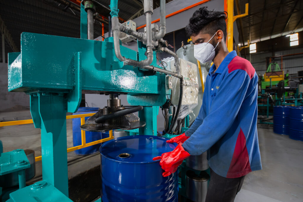 Ranama operator positioning a blue metal drum at reconditioning equipment