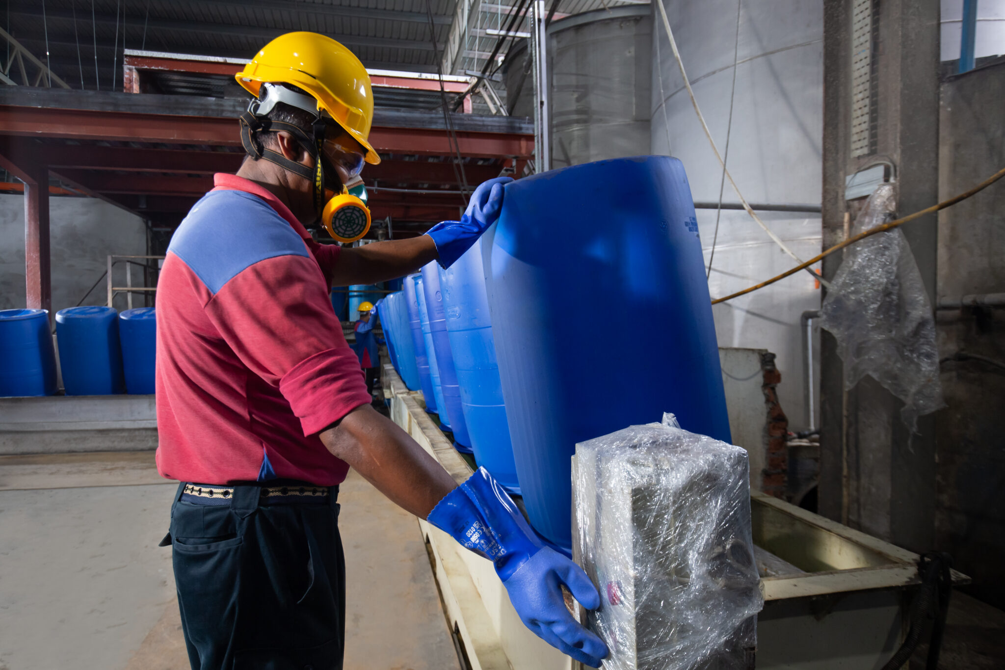 Ranama operator wearing protective equipment handling a blue industrial container