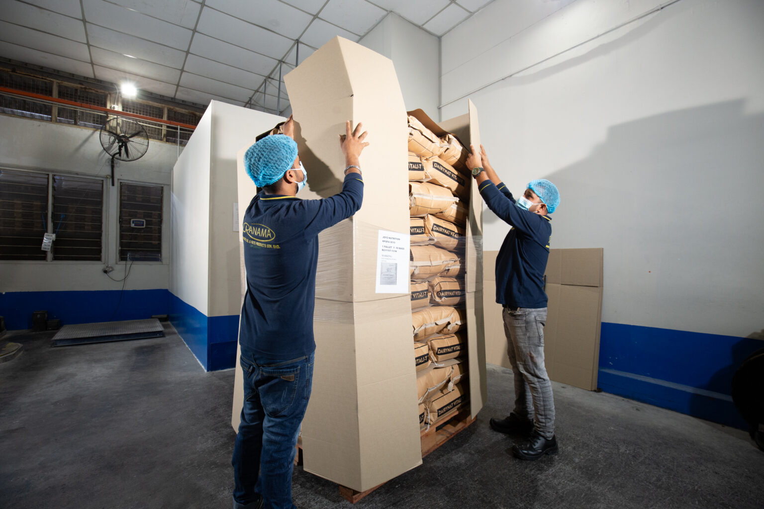 Ranama operators placing protective panels around palletised industrial paper sacks