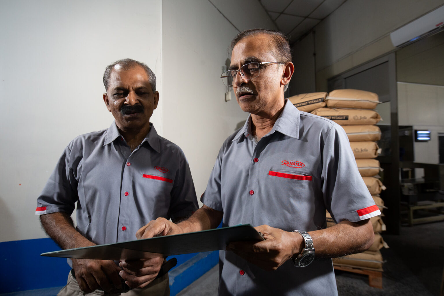 Two Ranama personnel reviewing information on a clipboard in the repackaging facility